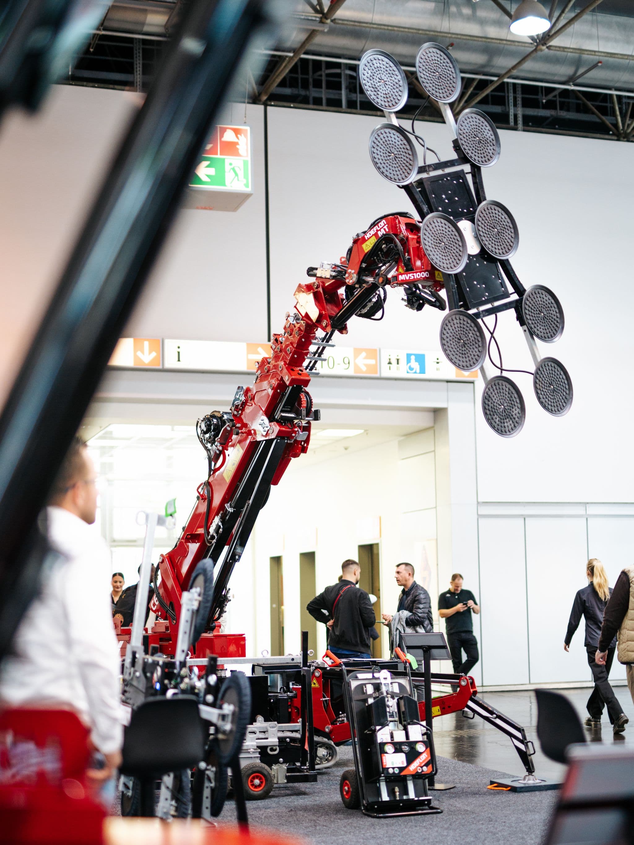 Hoeflon hijskraan tilt een object met een glaszuiger op een beurs.