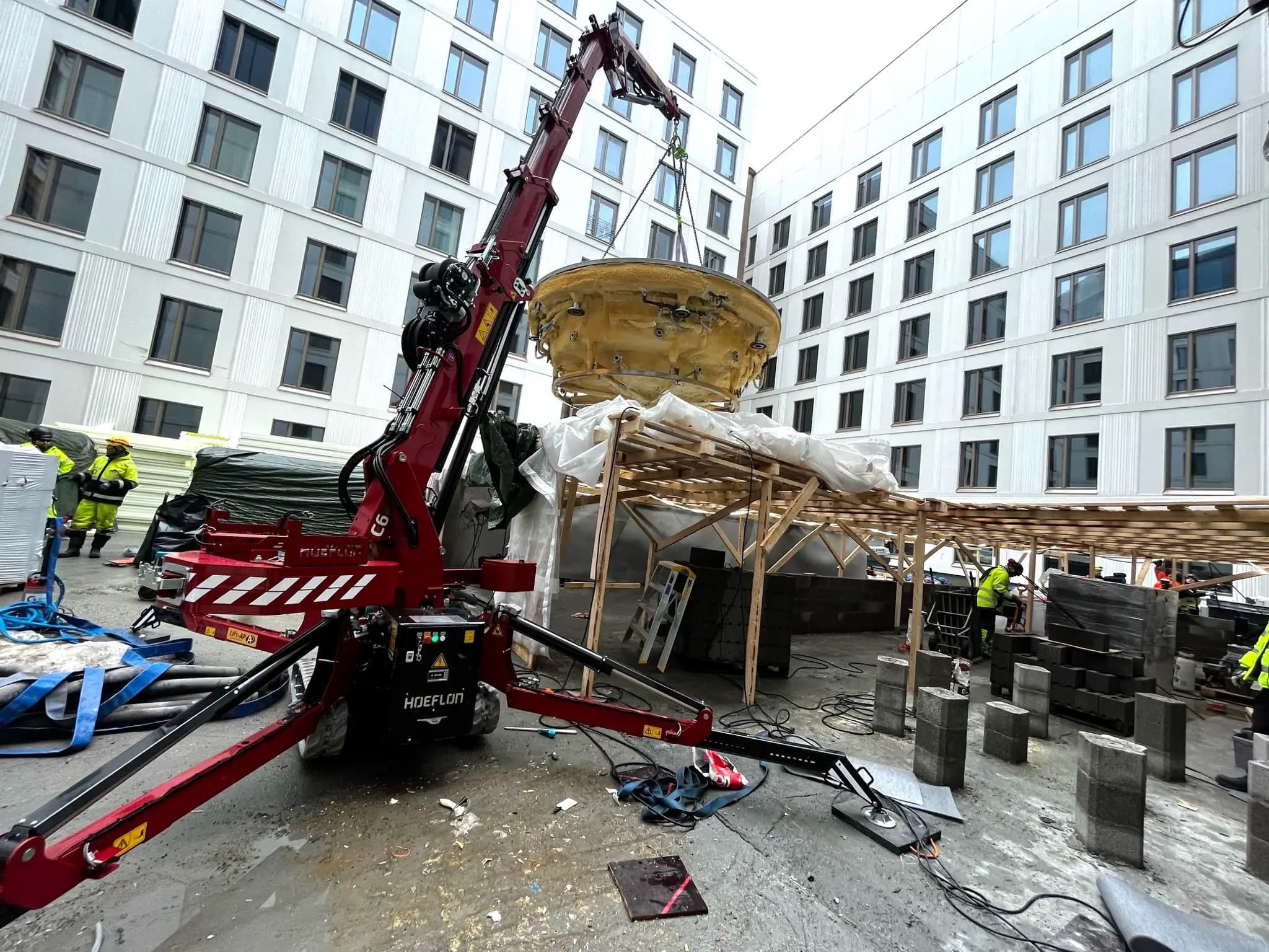 Hoeflon kraan hijst object op bouwplaats.