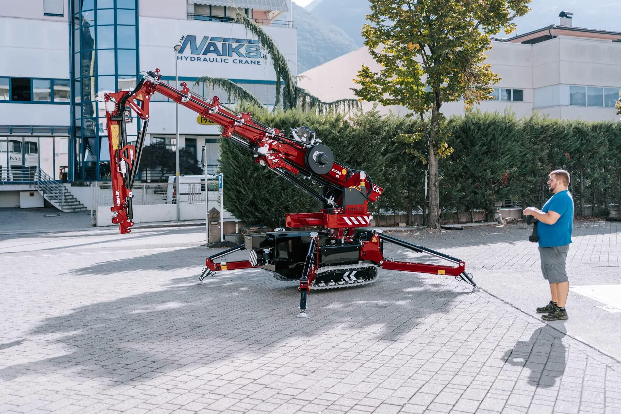 Hoeflon kraan in actie buiten, man bestuurt hijskraan met afstandsbediening.