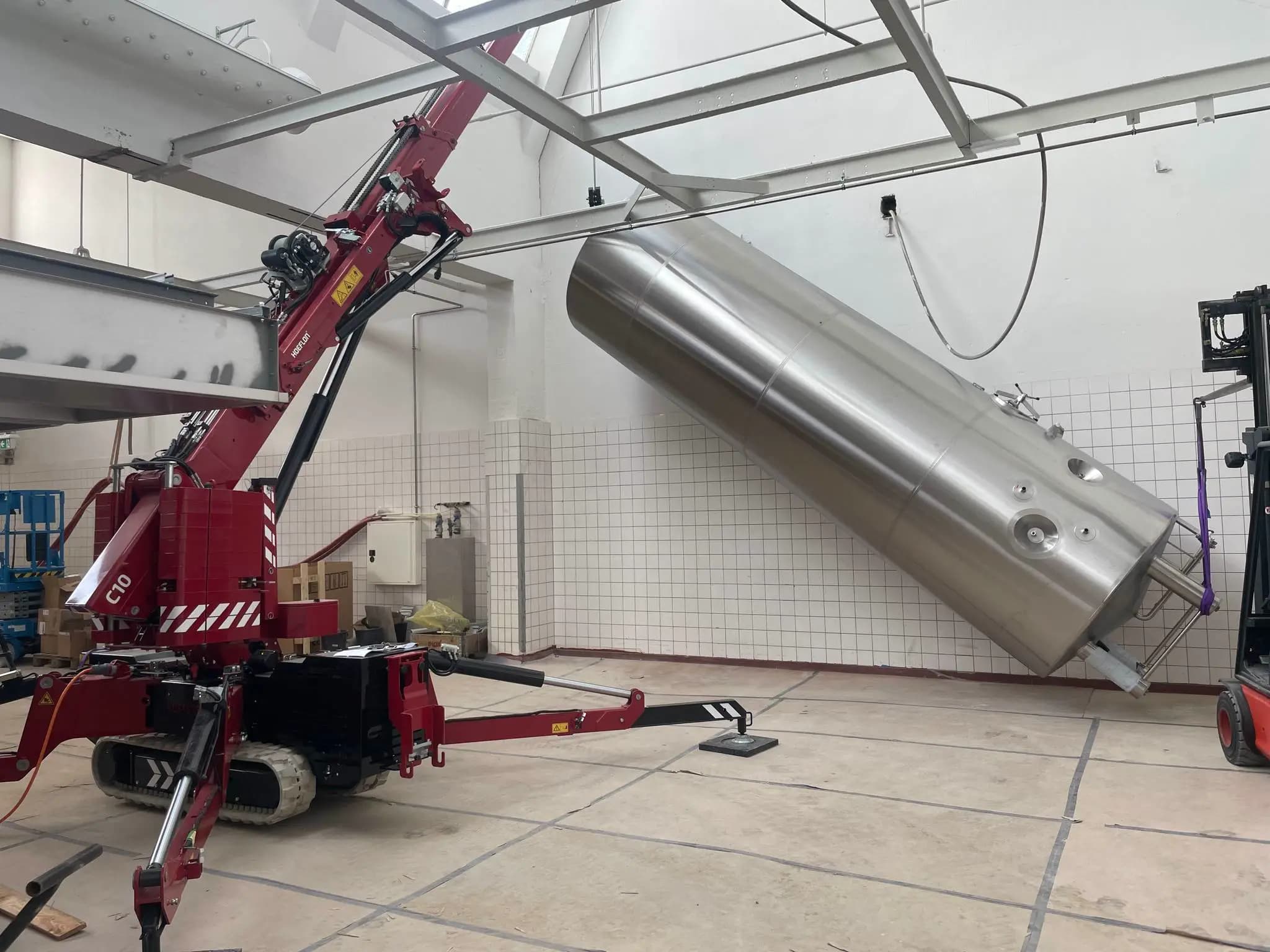 Hoeflon C10 hijst een grote cilinder in een fabriekshal.