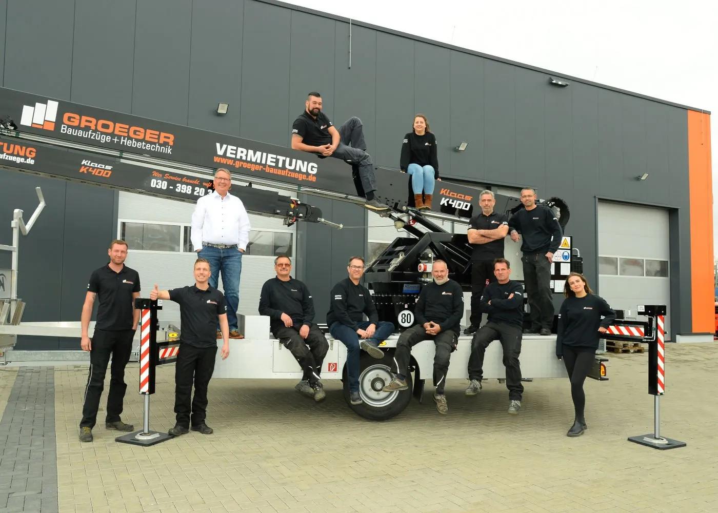 Teamfoto van Groeger Bauaufzüge met kraan op de achtergrond.